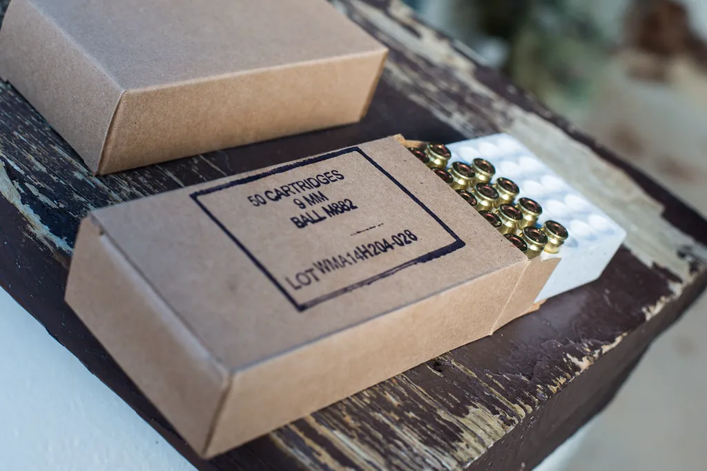 Open boxes of 9mm cartridges with brass rounds on a wooden counter
